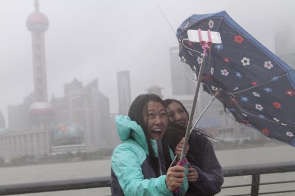 7月11日上午，上海，一些游客顶着台风在外滩防汛墙留影。 澎湃新闻记者 高剑平 图